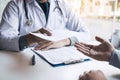 Asian male doctor talking in clinic room and handing a prescription to the patient Royalty Free Stock Photo