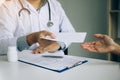 Asian male doctor talking in clinic room and handing a prescription to the patient Royalty Free Stock Photo