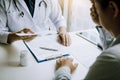 Asian male doctor talking in clinic room and handing a prescription to the patient Royalty Free Stock Photo