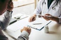 Asian male doctor talking in clinic room and handing a prescription to the patient Royalty Free Stock Photo