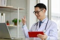 Asian male doctor talking and looking to camera in video conference