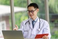 Asian male doctor talking and looking to camera in video conference