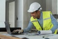 asian male engineer working with drawings inspection on laptop on construction site at work desk in office Royalty Free Stock Photo
