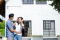 Asian male and female couples stand, hug, and smile happily in front of the new house. Royalty Free Stock Photo