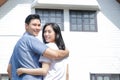 Asian male and female couples stand, hug, and smile happily in front of the new house. Royalty Free Stock Photo