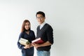 Asian male and female graduate students, wearing casual clothes, standing holding books and looking at the rear camera Royalty Free Stock Photo