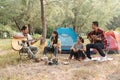 Asian male and female tourists are tenting and partying, chatting, singing and playing guitar in the forest Royalty Free Stock Photo