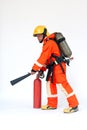 An Asian male firefighter in red protective uniform, mask and helmet with fire extinguisher standing on white background. Royalty Free Stock Photo