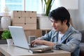 Asian man freelancer sitting on floor in living room and working online with laptop. Royalty Free Stock Photo