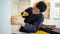 Asian male furniture assembler using tape measure