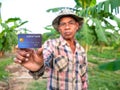 An Asian male gardener showing credit card in his banana garden