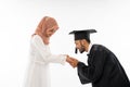 Asian male graduate student wearing toga shaking hands with mother Royalty Free Stock Photo