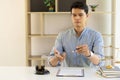 An Asian male lawyer works in an office with hammers and tiger skin scales on the table.