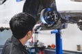 Asian male mechanical hold and shining flashlight to examine car disk brake pad wear of automotive vehicle. Safety suspension