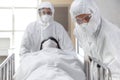 Asian male nurse and doctor wearing ppe suit and face mask pushing stretcher gurney bed with seriously infected coronavirus or Royalty Free Stock Photo