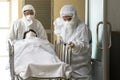 Asian male nurse and doctor wearing ppe suit and face mask pushing stretcher gurney bed with seriously infected coronavirus or Royalty Free Stock Photo