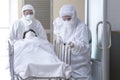 Asian male nurse and doctor wearing ppe suit and face mask pushing stretcher gurney bed with seriously infected coronavirus or Royalty Free Stock Photo