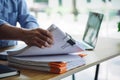 Asian male office worker holding documents of unfinished paperwork on office table