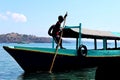 Asian male parking his boat over the sea, fisherman resting his wooden boat at the port or harbor area