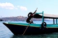 Asian male parking his boat over the sea, fisherman resting his wooden boat at the port or harbor area