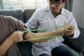 Asian male physical therapist descent working and helping to protect the hands of patients with patient doing stretching exercise Royalty Free Stock Photo