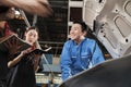 Supervisor engineer is teaching mechanic workers about car repair at a garage. Royalty Free Stock Photo