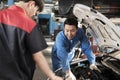 Supervisor engineer is teaching mechanic workers about car repair at a garage. Royalty Free Stock Photo