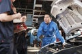 Supervisor engineer is teaching mechanic workers about car repair at a garage. Royalty Free Stock Photo