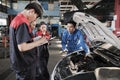 Supervisor engineer is teaching mechanic workers about car repair at a garage. Royalty Free Stock Photo