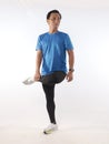 Asian male runner warming up prepararing his body before running workout. stretch his leg muscle, studio full length portrait Royalty Free Stock Photo