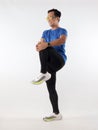 Asian male runner warming up prepararing his body before running workout. stretch his leg muscle, studio full length portrait Royalty Free Stock Photo