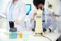 Asian male scientist examining virus specimen under a microscope in the lab with his coworker Royalty Free Stock Photo