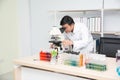 Scientist using Microscope in Laboratory. Male Researcher wearing white Coat sitting at Desk and looking at Samples.