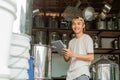 Asian male seller stands near a big pan when using tablet and look at camera