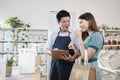 Asian male shopkeeper describe products to female customer in refill store