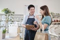 Asian male shopkeeper describe products to female customer in refill store