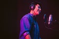 Asian male singer recording songs by using a studio microphone and pop shield on mic with passion in a music recording studio. Royalty Free Stock Photo
