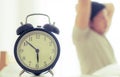 Male is stretching out after woke up with alarm clock showing six o clock Royalty Free Stock Photo