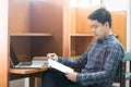 Asian male student reading a book in a library, Royalty Free Stock Photo