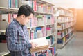 asian male student reading a book in a library, knowledge, education and school concept Royalty Free Stock Photo