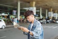 Asian male tourist reading map while waiting for taxi at the air Royalty Free Stock Photo