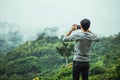 Asian male tourists take pictures of mountain landscapes after rain in northern Thailand.