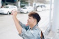 Asian male traveller taking photo while waiting for taxi at the