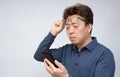 Asian male trying to read something on his mobile phone. poor sight, presbyopia, myopia.