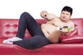 Asian male watching tv and holding donuts Royalty Free Stock Photo