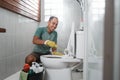 asian male wearing gloves brushing the dirty toilet