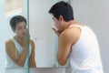 Asian man are applying moisturizer facial cream to his face after bathing and getting ready to work in the bathroom in the house Royalty Free Stock Photo