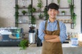 Asian man Barista or owner small business in apron looking at camera and arm crossed at the modern coffee shop