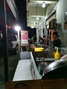 An asian man at burger stall preparing order for customer during night time