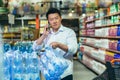 A Asian man buys pallets of water in a supermarket, Talking on the phone. Panic during quarantine